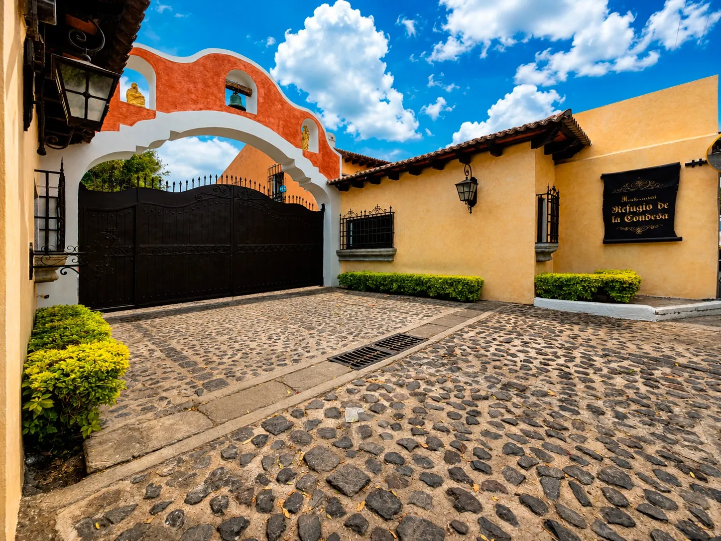 Entrada principal con arco de campana y portón de hierro